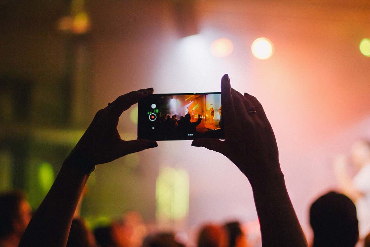 flora person holding smartphone while taking videos at live concert food